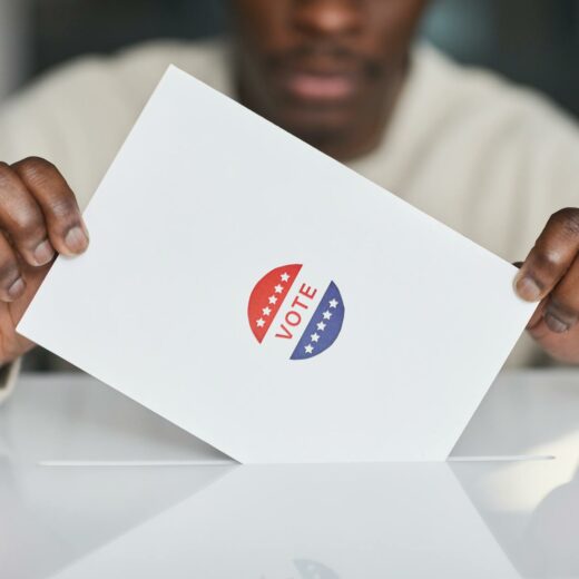 person putting a paper in white ballot box