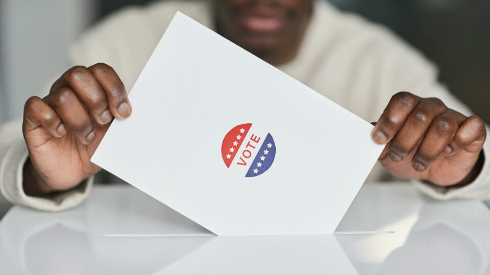 person putting a paper in white ballot box