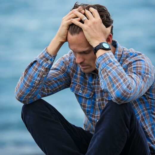 man in blue and brown plaid dress shirt touching his hair