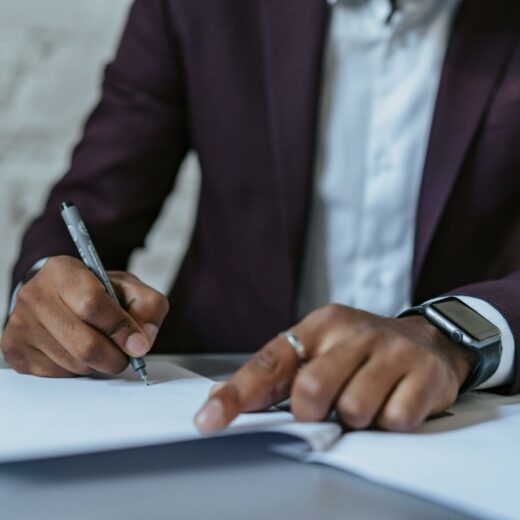 a man writing on white paper using a black pen