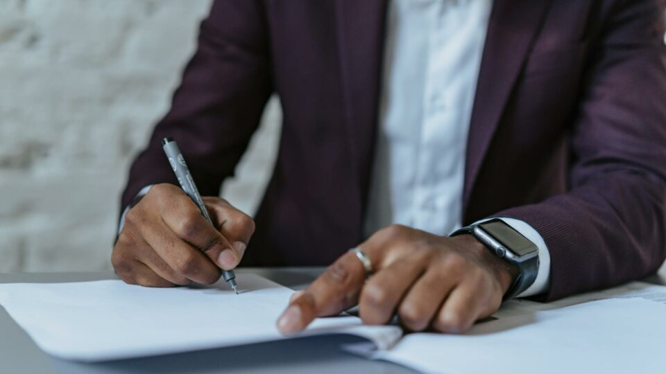 a man writing on white paper using a black pen