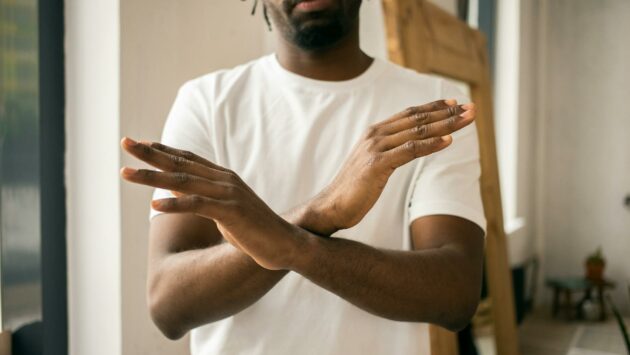 faceless black man showing stop gesture with crossed hands